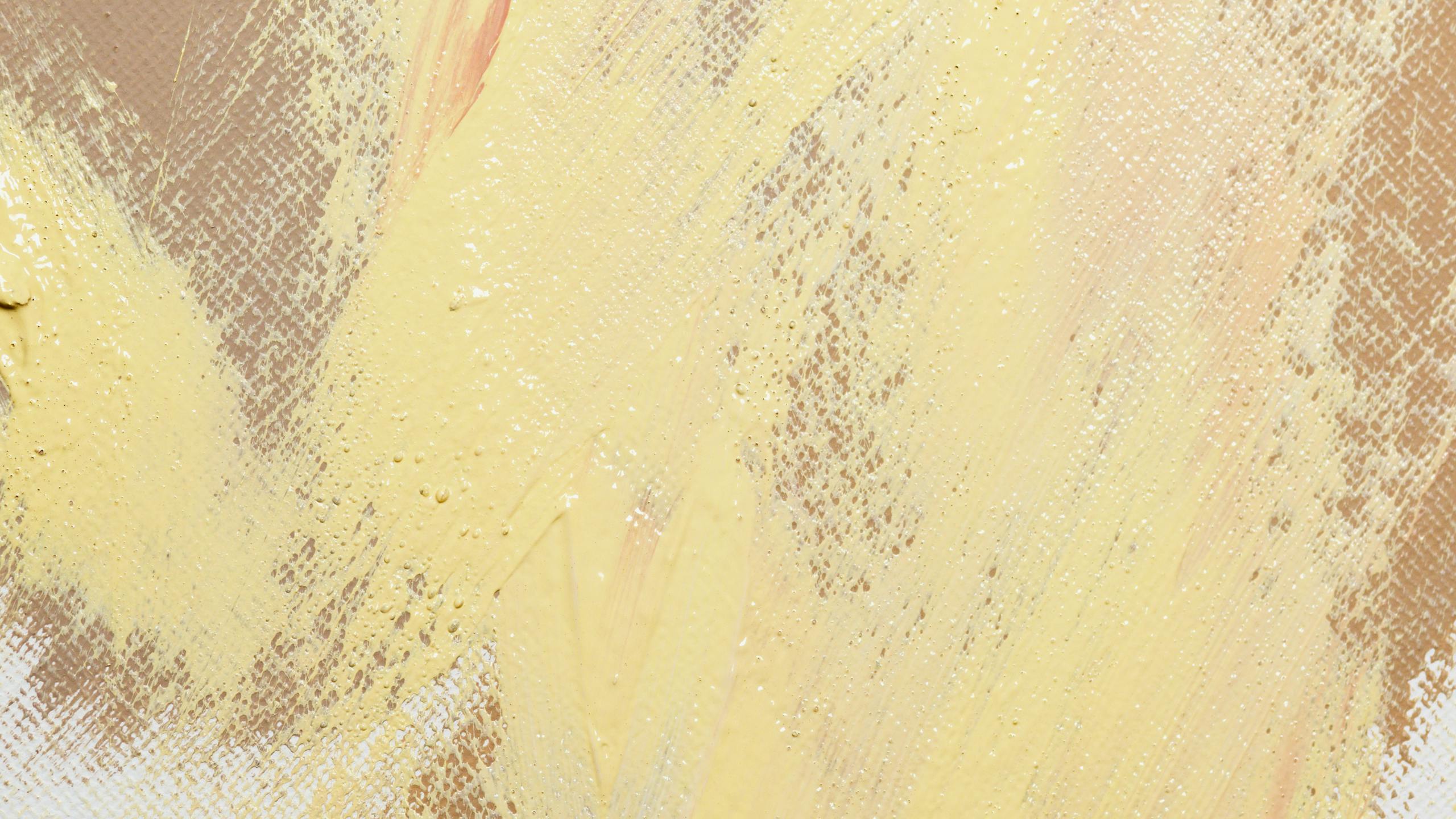 A close-up of an abstract painting with yellow and beige textured strokes on canvas.